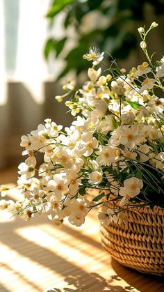 a basket filled with white flowers sitting on top of a wooden table next to a window