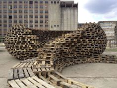 several wooden pallets stacked on top of each other in front of large building with tall windows