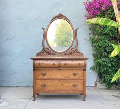 an old dresser with a mirror on top and flowers in the backgroung