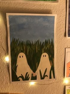 there are pictures on the wall with lights in front of them and two white ghostes holding hands