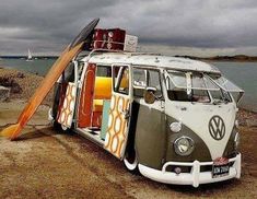 an old vw bus is parked on the beach with surfboards sticking out of it