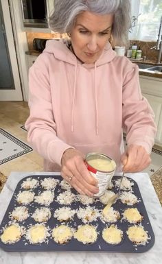 an older woman is making cookies and dipping them into a bowl with butter on top