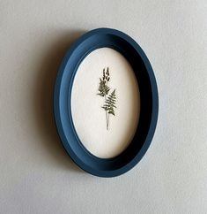 a blue and white plate with a plant in it's center on a wall