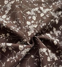 the fabric is brown with white flowers and leaves on it, as well as black background