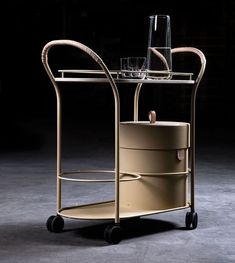 a metal cart with two cups on top and a wine glass in the middle, against a dark background