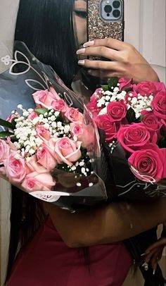 a woman holding a bouquet of pink roses and a cell phone in her right hand