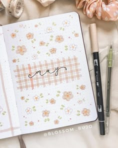 an open notebook with the word may written in cursive writing next to it