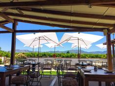 an outdoor dining area with tables and umbrellas over looking the mountains in the distance