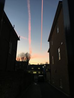 an airplane is flying in the sky over some houses and buildings at sunset or dawn