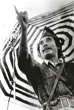 a man standing in front of an american flag with his hand up to the sky