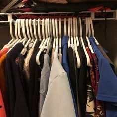 a rack with clothes hanging from it's sides and folded shirts on hangers