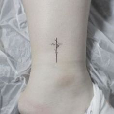 a small cross tattoo on the ankle