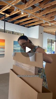 a woman opening up a cardboard box in an art gallery