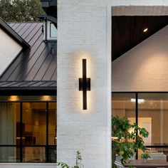 a white house with a cross on the wall and potted plants in front of it