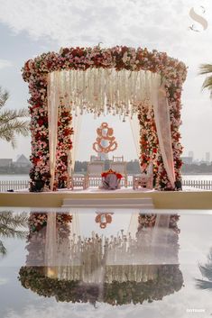 an outdoor wedding setup with flowers on the altar and chairs in front of it, surrounded by palm trees