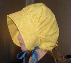 a woman wearing a yellow hat with a blue ribbon around it's brim