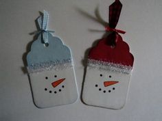 two tags with snowmen on them are hanging from the side of a white table