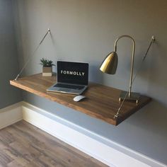 a laptop computer sitting on top of a wooden desk next to a lamp and potted plant