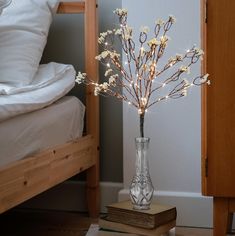 there is a vase with flowers in it on the floor next to a bed and pillows