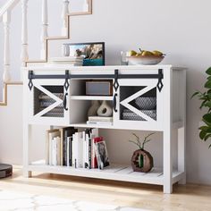 a white book shelf with books on it next to a stair case and potted plant