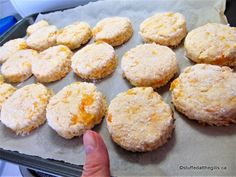 a person is pointing at some biscuits on a baking sheet with oranges in the background