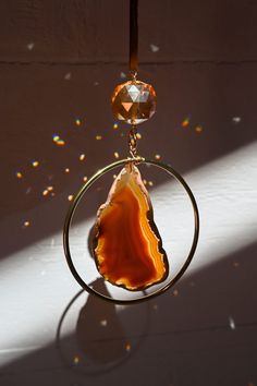 This beautiful suncatcher features a smooth Brown Agate gemstone set within a brass ring, creating a harmonious balance of earthy tones and luxurious warmth. Suspended beneath, a light-catching prism transforms sunlight into a dazzling dance of color, filling your space with positive energy and creating a tranquil ambiance. Brown Agate, renowned for its grounding properties, brings a sense of stability and connection to the natural world. As sunlight graces the surface of the agate, it not only Agate Slice Sun Catcher, Agate Suncatcher, Copper Agate, Brown Agate, Rock Jewelry, Hanging Decorations, Brass Ring, Sun Catcher, Agate Gemstone