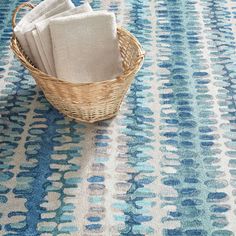 a basket filled with white towels sitting on top of a blue rug