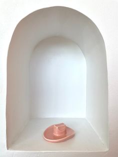 a white shelf with a pink object in it