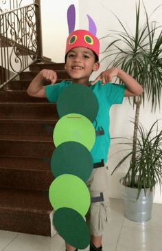 a young boy is holding up a very large caterpillar shaped cardboard cutout