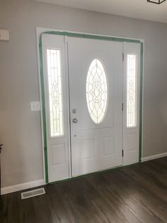 the front door is painted white and has two stained glass panels on each side, along with hardwood flooring