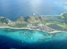 an aerial view of the ocean and island in the middle of the ocean with blue water