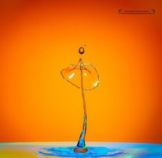 an orange and blue background with water splashing on the surface, as if it were floating