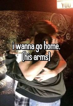 a woman hugging her boyfriend in front of a sign that says i wanna go home this arms