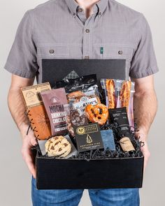 a man holding a box full of snacks