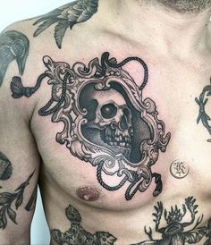 a man with tattoos on his chest has a skull in a frame