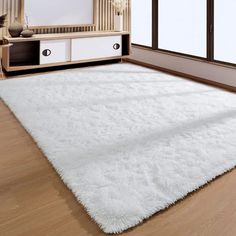 a large white rug is in the middle of a room with wooden floors and windows