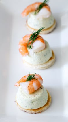 three small crackers with shrimp and cream cheese on them are sitting on a white plate