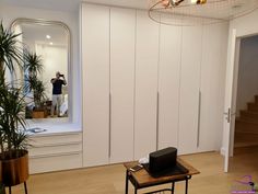 a living room with white walls and wooden flooring next to a large mirror on the wall