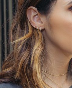 a close up of a person wearing ear rings and a necklace with gold chains on it