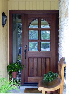 a wooden front door with two planters on either side and a bench in front