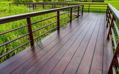 a wooden deck with metal railings in the grass