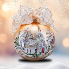 a glass ornament with a white bow on it's side and snowflakes in the background