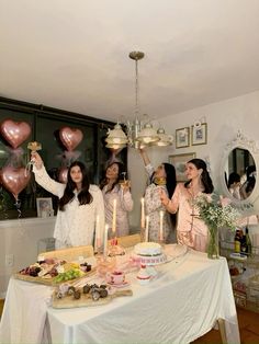 a group of women standing around a table holding up heart shaped balloons