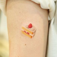 a small piece of cake on the back of a woman's leg with a strawberry painted on it