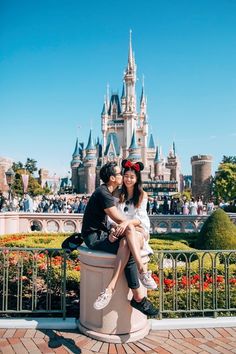 a man and woman sitting on top of a statue in front of a castle