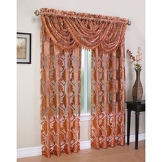 an orange curtain hanging on the side of a window next to a vase with flowers