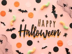 the word happy halloween spelled out in black and orange letters on a pink background with bats, spider webs, and pumpkins