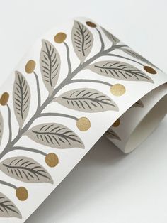 a roll of white and gold foiled paper with leaves printed on it's sides