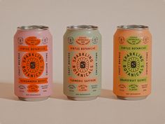 three cans of orange, pink and green beverage