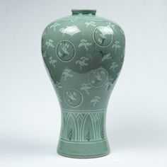 a green vase sitting on top of a white table